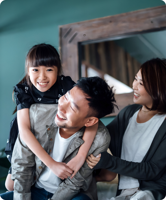 Happy family at home: Dad gives daughter a piggyback ride while mom smiles.