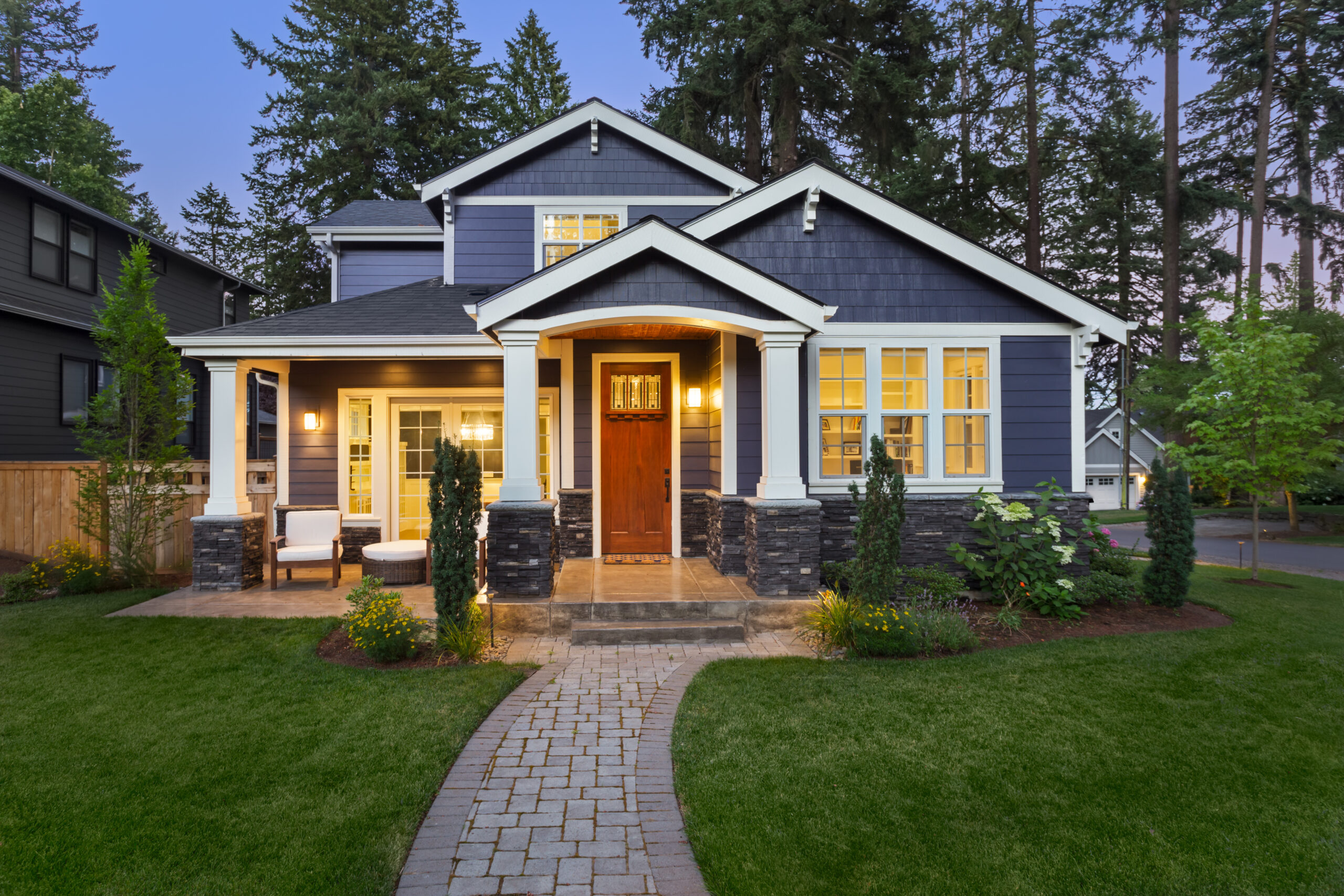 Beautiful blue craftsman home with a brick pathway and well-manicured lawn.
