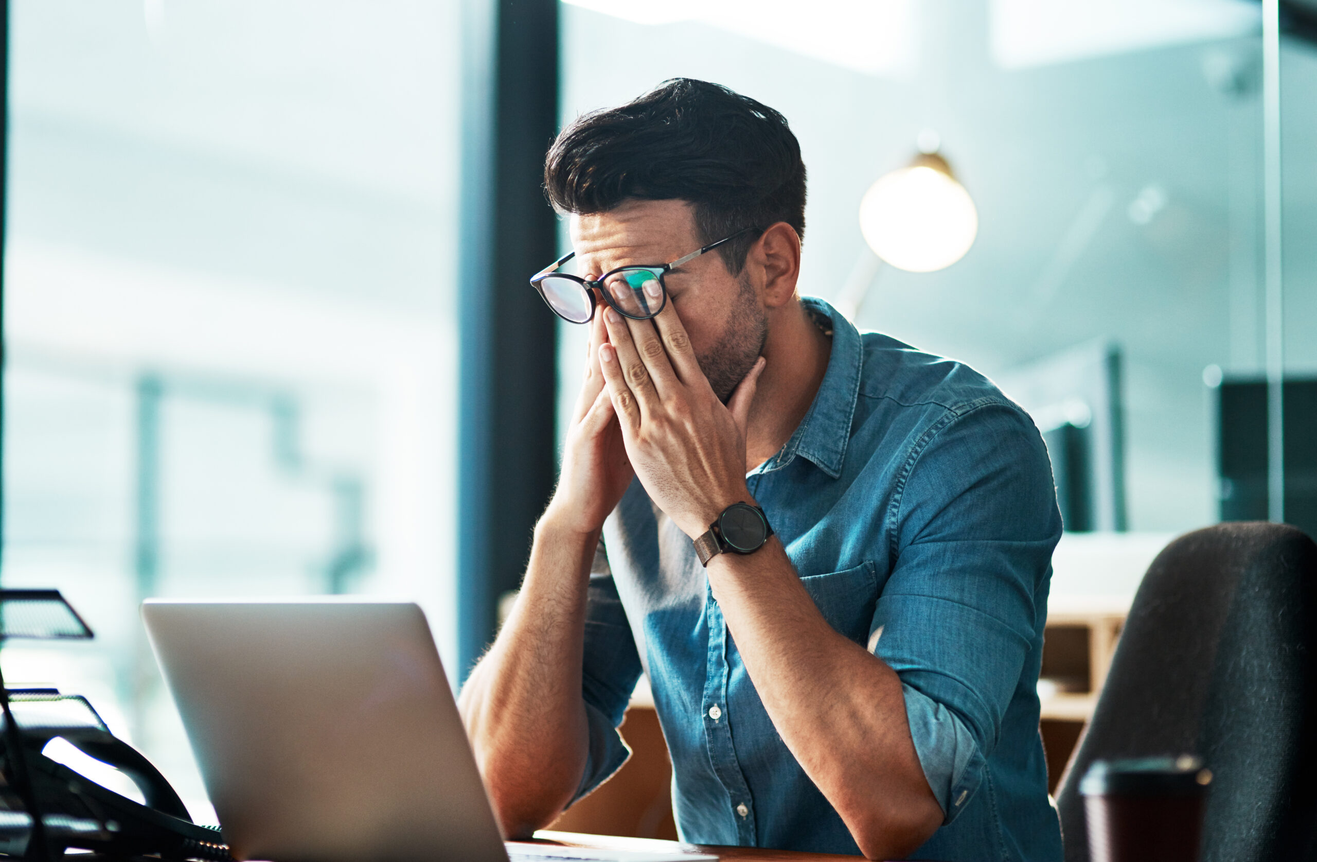 Stressed man at laptop rubbing eyes, likely facing commercial lines challenges.