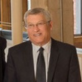 Dennis Kanin in a suit and tie, smiling confidently.